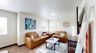 Located at 15 Tri-Park Way in Appleton, Wisconsin, this single-floor unit offers four bedrooms, two bathrooms, a shared living room, and a connecting hallway. The layout is designed for efficient use of space, with wood-look flooring running through the common areas and carpet in the bedrooms.

Each bedroom is furnished with a bed frame, desk, and chair, and features a window with blinds that brings in natural light and views of surrounding greenery. The primary bedroom is notably more spacious and includes an open closet with a clothing rod, a dresser, and wall-mounted television. The remaining bedrooms follow a consistent, functional design.

The two bathrooms are clean and practical, featuring wood-look tile flooring, a toilet, sink, and shower-tub combination with a curtain rod. The hallway connects the bedrooms and bathrooms with ease of circulation.

The shared living room serves as the communal hub of the unit, featuring hardwood-style flooring, large windows on two walls that flood the space with natural light and outdoor views, a wall-mounted television, and seating. A bold geometric wall piece adds a vibrant visual accent to the otherwise neutral palette. The overall design is straightforward, modern, and well-suited for shared occupancy.