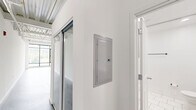 Located at 4151 Main St in Philadelphia's vibrant Manayunk neighborhood, this single-floor unit offers a striking industrial-modern aesthetic that makes efficient use of its well-planned layout. The open living area immediately impresses with soaring exposed steel truss ceilings, polished concrete floors, and a dramatic wall of floor-to-ceiling windows that flood the space with natural light and frame verdant outdoor views. A ceiling fan adds both function and style to this airy main area.

The kitchen is a standout feature, designed with clean white cabinetry, granite countertops, a subway tile backsplash, and a peninsula with an undermount sink and matte black faucet. Stainless steel appliances — including a refrigerator, range, and microwave — complete the modern setup, while pendant lighting overhead enhances the industrial character of the space.

Two bathrooms maintain the unit's contemporary theme, each finished with large-format white tile flooring, floating wood-toned vanities with white basin sinks, matte black fixtures, and frameless mirrors. The crisp, all-white palette creates a clean and serene atmosphere throughout. A hallway connects the spaces efficiently, rounding out a thoughtfully designed unit that balances urban industrial style with modern comfort.