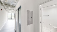 Located at 4151 Main St in Philadelphia's vibrant Manayunk neighborhood, this single-floor unit offers a striking industrial-modern aesthetic that makes efficient use of its well-planned layout. The open living area immediately impresses with soaring exposed steel truss ceilings, polished concrete floors, and a dramatic wall of floor-to-ceiling windows that flood the space with natural light and frame verdant outdoor views. A ceiling fan adds both function and style to this airy main area.

The kitchen is a standout feature, designed with clean white cabinetry, granite countertops, a subway tile backsplash, and a peninsula with an undermount sink and matte black faucet. Stainless steel appliances — including a refrigerator, range, and microwave — complete the modern setup, while pendant lighting overhead enhances the industrial character of the space.

Two bathrooms maintain the unit's contemporary theme, each finished with large-format white tile flooring, floating wood-toned vanities with white basin sinks, matte black fixtures, and frameless mirrors. The crisp, all-white palette creates a clean and serene atmosphere throughout. A hallway connects the spaces efficiently, rounding out a thoughtfully designed unit that balances urban industrial style with modern comfort.