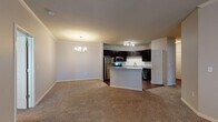 This single-floor residence offers a thoughtfully designed open-concept layout that seamlessly connects the living, dining, and kitchen areas. The kitchen is a standout feature, showcasing rich dark cabinetry, granite countertops, a classic white subway tile backsplash, and a full suite of stainless steel appliances including a range, microwave, refrigerator, and dishwasher. A central island with a granite surface provides additional prep space and serves as a natural divider between the kitchen and the adjacent living and dining areas. The dining area is accented by a stylish chandelier, while the spacious living room features plush carpeting and a ceiling fan with integrated lighting. A built-in desk nook adds a practical workspace to the main living area. The bedrooms are generously sized, each with soft carpeting, neutral tones, and windows that allow natural light to filter in. The bathroom is well-equipped with dark wood cabinetry, granite countertops, a large vanity mirror, and a full tub-shower combination. Consistent use of neutral color palettes, crown molding details, and hardwood-style flooring in the kitchen create a cohesive and inviting atmosphere throughout the home.
