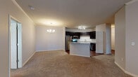 This single-floor residence offers a thoughtfully designed open-concept layout that seamlessly connects the living, dining, and kitchen areas. The kitchen is a standout feature, showcasing rich dark cabinetry, granite countertops, a classic white subway tile backsplash, and a full suite of stainless steel appliances including a range, microwave, refrigerator, and dishwasher. A central island with a granite surface provides additional prep space and serves as a natural divider between the kitchen and the adjacent living and dining areas. The dining area is accented by a stylish chandelier, while the spacious living room features plush carpeting and a ceiling fan with integrated lighting. A built-in desk nook adds a practical workspace to the main living area. The bedrooms are generously sized, each with soft carpeting, neutral tones, and windows that allow natural light to filter in. The bathroom is well-equipped with dark wood cabinetry, granite countertops, a large vanity mirror, and a full tub-shower combination. Consistent use of neutral color palettes, crown molding details, and hardwood-style flooring in the kitchen create a cohesive and inviting atmosphere throughout the home.