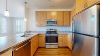 Located at 5959 Dunkirk St in Denver, CO, this single-floor, 3-bedroom, 2-bathroom home offers a thoughtfully designed layout with consistent hardwood-style flooring throughout. The kitchen is a functional standout, featuring warm maple cabinetry, granite-style countertops, a full suite of stainless steel appliances including a range, over-the-range microwave, and refrigerator, plus a pendant light accent and a double-basin sink. The open hallway connects the main living areas seamlessly, drawing natural light from the bright living room, which is lined with large windows fitted with vertical blinds that offer ample sunlight and exterior views. The three bedrooms are clean and neutral, with warm-toned flooring and natural light. The primary bedroom provides a generous footprint with dedicated closet space. Both bathrooms are finished with wood-toned vanities and white countertops. A dedicated laundry room includes a washer and overhead cabinetry for added storage. Four closets throughout the home ensure excellent storage capacity. A private balcony rounds out this well-organized home, offering an outdoor retreat within this Denver community.