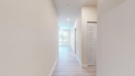 This single-floor residence presents a clean, contemporary design throughout, with light wood-look flooring and a neutral color palette that create a cohesive, airy atmosphere from entry to each room. A well-proportioned hallway leads from the entrance into the main living areas, with a louvered storage closet providing convenient organization near the entry.

The kitchen is a standout feature, offering generous cabinetry in a soft gray-white finish with shaker-style doors, a subway tile backsplash, and a large quartz island countertop ideal for meal preparation or casual dining. A full suite of stainless steel appliances, including a refrigerator with ice maker, electric range, microwave, and dishwasher, completes the space. A window above the sink brings in natural light.

The bedrooms are comfortably sized, each featuring ceiling fans, windows with outdoor views, and light flooring. A walk-in closet with wire shelving systems provides ample storage. The bathroom is neatly appointed with a vanity, light countertops, and wood-look flooring. A dedicated in-unit laundry room houses a full-sized washer and dryer with overhead shelving. The attached garage offers additional storage and parking.