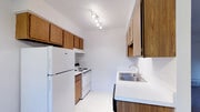 Located at 6851 Sharon Ct in Columbus, Ohio, this single-floor residence offers a functional and straightforward layout designed for comfortable everyday living. The galley-style kitchen is efficiently arranged with warm wood-toned cabinetry lining both walls, providing ample storage from floor to ceiling. White countertops offer a clean contrast, while tile flooring, a stainless steel sink, a dishwasher, a range, and a full-size refrigerator complete the space. A pass-through opening connects the kitchen to the adjacent living area, which transitions seamlessly via a half-wall partition. The living room features wall-to-wall carpeting, a ceiling fan with light fixture, a textured ceiling, and multiple windows fitted with blinds that allow natural light to fill the room. The bedroom is generously sized with soft carpeting, a dedicated closet with built-in shelving, and additional access to surrounding rooms. The full bathroom includes a tiled shower-tub combination, a vanity with a white countertop, and tile flooring. Throughout the unit, neutral tones and consistent finishes create a cohesive, move-in-ready atmosphere suited for a range of residents.
