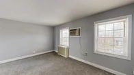 Located at 100 Arcadia Rd in Hackensack, NJ, this two-bedroom, one-bathroom unit is spread across two floors, with the main living areas on the upper level. The kitchen is a standout feature, showcasing rich dark wood cabinetry, granite countertops, a white subway tile backsplash, and light hardwood-style flooring. Stainless steel appliances — including a refrigerator, dishwasher, and gas range — complete the well-equipped space. The combined living and dining area offers a functional open layout, ideal for everyday living. A dark-carpeted staircase with a sleek black handrail connects the floors, leading to a hallway that serves the bedrooms. Both bedrooms are carpeted and painted in soft gray tones, each featuring multiple windows that invite natural light and views of the surrounding neighborhood. Wall-unit air conditioners and radiator covers are present in the bedrooms, providing year-round climate control. Three closets offer ample storage throughout. The full bathroom includes a soaking tub with full tile surround in neutral beige tones and a window for natural ventilation. With three closets and a practical layout, this unit offers comfortable, well-organized living in a residential Hackensack setting.