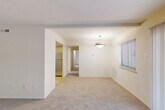 Located at 8731 Contee Rd in Laurel, Maryland, this single-floor residence offers a well-organized layout comprising two bedrooms, three bathrooms, a living room, kitchen, hallway, and four closets. The living room is a bright, open space featuring soft carpeting, neutral white walls, and a central pendant light fixture. Natural light enters through windows dressed with blinds, and a sliding door with vertical blinds provides additional light and access. The kitchen is equipped with light wood cabinetry, dark countertops, tile flooring, and stainless steel appliances including a range and over-the-range microwave. The spacious primary bedroom features plush carpeting, ample wall space, and direct access to a private en-suite bathroom outfitted with a wood-toned vanity and a round mirror. The second bedroom is also carpeted and benefits from a window with natural views. The bathrooms are clean and functional, with at least one featuring a full tub-shower combination with classic white subway tile surround and chrome fixtures. Throughout the residence, the consistent use of neutral tones and carpet creates a cohesive and comfortable living environment.