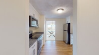 Located at Broad Reach in Weymouth, Massachusetts, this single-floor residence offers a thoughtfully designed layout with bright, open living spaces and quality finishes throughout. The living room is generously sized, bathed in natural light through large picture windows and sliding glass doors that lead to a private balcony with open exterior views—creating a seamless indoor-outdoor connection. Warm neutral tones and plush carpeting contribute to a relaxed, coastal ambiance.

The kitchen is well-equipped with white shaker cabinetry, granite countertops, stainless steel appliances including a range, over-the-range microwave, and refrigerator, all set atop light hardwood-style flooring. It flows directly into a dedicated dining area, illuminated by a chandelier and large sliding door, ideal for everyday meals or entertaining.

Two bedrooms offer comfortable retreats, each with plush carpeting and natural light. The primary bedroom features a wide window with exterior views. Both bathrooms are finished with granite countertops, undermount sinks, and tile flooring, with one offering an extended vanity and a large mirror. The overall layout is functional and cohesive, delivering a bright, move-in-ready living experience.