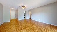 Located at 1437 Central Ave in Memphis, Tennessee, this single-floor unit offers a well-organized layout comprising two entrance areas, a kitchen, a bathroom, and a connecting hallway. The main living area is a bright, open space highlighted by classic parquet wood flooring in a basket-weave pattern and a ceiling fan with a light fixture overhead. A textured ceiling adds subtle character, while large sliding glass doors lead to a private balcony, flooding the room with natural light and providing pleasant views of the surrounding greenery. The entrance opens directly into this central living space, creating a welcoming and functional flow throughout the unit. The kitchen is efficiently designed with ample white cabinetry extending to the ceiling for generous storage, dark granite-style countertops, a stainless steel sink, a refrigerator, and a dishwasher. Light tile flooring gives the kitchen a clean, practical finish. The bathroom features classic tile work, including a mosaic tile floor and tiled tub surround, a wall-mounted sink, and a shower-tub combination. The hallway connects the main rooms cohesively, contributing to the unit's practical and straightforward layout. Overall, the space offers a functional and comfortable environment in a central Memphis location.