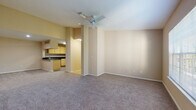 This single-floor residence offers a thoughtfully designed layout that balances comfort and functionality. The open-concept living area is finished with neutral-toned carpet and warm beige walls, creating a welcoming atmosphere. A ceiling fan overhead provides practical climate control, while the space flows seamlessly into the kitchen via a pass-through counter with dark granite-style countertops — ideal for both everyday living and entertaining.

The kitchen is well-appointed with light wood cabinetry extending to the ceiling for ample storage, matching dark countertops, tile flooring, and full appliances including a dishwasher, electric range, and refrigerator. A dedicated dining area adjacent to the kitchen pass-through adds convenience.

The bedrooms are generously sized, each featuring plush carpeting, ceiling fans, and large windows that invite natural light and offer views of surrounding greenery. The rooms provide a calm, restful environment with plenty of wall space for flexible furniture arrangements.

Both bathrooms are finished with wood-look flooring, light wood vanities, dark countertops, and tub-shower combinations. Natural light filters in through windows, enhancing the clean, functional design. Throughout the unit, consistent neutral tones and practical finishes create a cohesive and move-in-ready living space.
