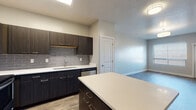 This thoughtfully designed single-floor unit offers a cohesive modern aesthetic throughout. The open-concept kitchen and living area serves as the heart of the space, anchored by a central island with a white quartz countertop and dark cabinetry. The kitchen is fully equipped with stainless steel appliances, including a refrigerator, range, and microwave, complemented by a grey subway tile backsplash and ample upper and lower cabinet storage. Wood-look luxury vinyl plank flooring extends through the main living areas, lending warmth and visual continuity.

The bedrooms feature plush carpeting and windows fitted with blinds that allow natural light to fill the rooms. One bedroom includes access to a walk-in closet, providing generous storage. The neutral wall tones throughout create a calm, versatile backdrop.

Two bathrooms mirror the home's consistent design language, each featuring dark floating vanities topped with white quartz countertops, undermount sinks, brushed nickel fixtures, and wood-look flooring. One bathroom includes a tub-shower combination, while the other offers a more open layout with a full-width vanity and large mirror. Together, the spaces present a clean, contemporary living environment well-suited for everyday comfort.