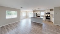 This single-floor unit at 4301 Breton Rd SE in Grand Rapids, Michigan, presents a clean, modern aesthetic throughout. The open-concept layout connects the living area and kitchen seamlessly, with light wood-tone luxury vinyl plank flooring extending across the main living spaces, allowing natural light from multiple windows to enhance the bright, airy atmosphere.

The kitchen is well-appointed with white shaker-style cabinetry, a classic subway tile backsplash, and a full suite of stainless steel appliances, including a range, over-the-range microwave, dishwasher, and refrigerator. A central island with a gray countertop provides additional workspace and serves as a natural divider between the kitchen and living area. Pendant lighting above the island adds a refined touch.

The bedrooms feature neutral-toned carpeting and windows that bring in natural light. Each room offers closet space and is finished with clean white trim throughout. The bathrooms are outfitted with light wood-tone vinyl flooring, white vanity cabinetry with gray countertops, and full tub-shower combinations with brushed nickel fixtures. The overall palette—neutral walls, white trim, and consistent finishes—creates a cohesive, move-in-ready environment.