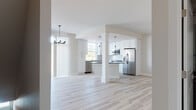 This two-floor space offers a clean, modern aesthetic defined by a neutral color palette, light-toned luxury vinyl plank flooring on the main level, and thoughtful design throughout. The open-concept main floor centers around a well-equipped kitchen featuring crisp white shaker-style cabinetry, dark countertops, a subway tile backsplash, and a full suite of stainless steel appliances including a refrigerator with ice maker, electric range, built-in microwave, and dishwasher. A central island with pendant lighting above provides additional prep space and separates the kitchen from the adjoining living area. Natural light filters in through multiple windows fitted with blinds. A half bathroom on the main level includes a dark-cabineted vanity with a taupe countertop and wood-look flooring. Upstairs, the bedrooms are finished with plush carpet and ceiling fans, each with natural window views. The upper-level bathrooms are well-appointed, featuring dark espresso cabinetry, taupe countertops, large mirrors, and a tiled shower with sliding glass doors in one full bath, alongside a medicine cabinet for storage.