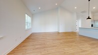 Located at 16374 Granite Way in Milton, Delaware, this well-appointed single-story home offers three bedrooms and three full bathrooms across a generously sized floor plan. Light oak hardwood flooring flows throughout the main living areas and bedrooms, complemented by crisp white walls that create a bright, airy atmosphere. The open-concept kitchen and living room serve as the heart of the home, featuring white shaker cabinetry with matte black hardware, white subway tile backsplash, quartz countertops, and stainless steel appliances. Three hallways connect the living spaces seamlessly, with recessed lighting and wide pathways providing an open, unobstructed feel. The spacious primary bedroom boasts vaulted ceilings and two large windows that fill the room with natural light. Secondary bedrooms are well-sized with hardwood floors and natural light from bright windows. The bathrooms are finished with elegant herringbone-patterned tile flooring, subway tile shower surrounds, and matte black fixtures, adding a modern contrast to the clean white palette. A dedicated laundry room provides added convenience. The attached garage features a concrete floor, automatic opener, and electrical panel access, completing this thoughtfully designed home.
