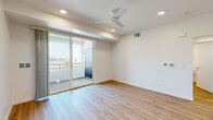 This single-floor unit in the 95330 zip code of California presents a contemporary design defined by clean lines, bright white walls, and warm wood-look flooring that runs consistently throughout the space. The open layout is well-lit, with recessed lighting and natural light filtering in from multiple windows and glass sliding doors.

The main living area is generously sized and includes a ceiling fan, recessed lighting, and sliding glass doors that open onto a private balcony with outdoor views of surrounding greenery—an inviting feature that enhances the sense of openness. A separate bedroom offers a large window with natural light and tree-line views, as well as its own door for privacy.

The kitchen is outfitted with glossy white cabinetry, light stone countertops, a stainless steel sink, and a full suite of stainless steel appliances including a refrigerator, range, microwave, and dishwasher. The layout is efficient and functional.

Two bathrooms serve the unit. One features a sleek, flat-panel vanity with white countertops and a large mirror. The other includes a glass-enclosed walk-in shower. Both continue the wood-look flooring and maintain the unit's clean, modern aesthetic throughout.