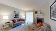This single-floor residence offers a thoughtfully designed layout that balances comfort and functionality across its living spaces. The living room serves as a welcoming centerpiece, featuring plush carpet, a classic tile-surround fireplace with a white mantel, and a large sliding glass door framed by vertical blinds that floods the room with natural light and provides access to the outdoors. The galley-style kitchen is efficiently appointed with white shaker cabinetry, granite countertops, stainless steel appliances including a microwave, dishwasher, and refrigerator, and wood-look flooring that extends into the adjacent dining area. A peninsula with a granite countertop connects the kitchen to the main living space, offering additional prep and seating potential. The dedicated dining nook accommodates a round table beneath a pendant light fixture, creating an intimate setting for meals. Both bedrooms are carpeted and generously sized, each benefiting from natural light through windows with outdoor views. The primary bedroom includes direct access to a closet. The bathroom features clean tile work and a tub-shower combination. Neutral tones, consistent trim work, and flush-mount lighting contribute to a cohesive and comfortable ambiance throughout.