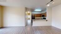 This single-floor, 3-bedroom, 2-bathroom residence in Layton, Utah offers a functional and comfortable layout designed for everyday living. The open-concept kitchen and living area serves as the heart of the home, where rich warm-toned wood cabinetry pairs with granite-style countertops, a full suite of black appliances—including a gas range, microwave, refrigerator, and dishwasher—and a peninsula with bar seating. The kitchen flows seamlessly into the living area, which features durable wood-look vinyl flooring, a ceiling fan with light fixture, and a sliding glass door that invites natural light and outdoor access. A long hallway connects the common areas to the private bedrooms, each finished with plush wall-to-wall carpet and windows fitted with blinds for natural light and privacy. The spacious primary bedroom includes a dedicated walk-in closet outfitted with built-in shelving and hanging rods. Both bathrooms are finished with wood-look vinyl flooring, warm wood vanity cabinetry, and tub-shower combinations. Neutral wall tones throughout the home create a clean, move-in-ready aesthetic, while consistent flooring materials and thoughtful storage solutions contribute to a cohesive and practical living environment.