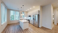 Located at 222 N West St in downtown Raleigh, NC, this well-designed 2-bedroom, 1-bathroom residence offers a thoughtful layout across a single floor. The open-concept living area seamlessly integrates the kitchen, dining, and living spaces, creating a bright and functional hub for everyday living. The kitchen is outfitted with stainless steel appliances — including a refrigerator, range, microwave, and dishwasher — complemented by sleek white quartz countertops, a subway tile backsplash, and ample cabinetry. A central island provides additional prep and storage space, illuminated by stylish globe pendant lights. Large windows throughout the unit allow natural light to fill each room, with views of the surrounding Raleigh cityscape. Light wood-style flooring runs continuously throughout the unit, enhancing the clean, modern aesthetic. The spacious primary bedroom features a ceiling fan and generous closet space, while the second bedroom also benefits from large windows and its own closet. The bathroom is finished with a subway tile tub surround, a white vanity, and wood-style flooring. Additional spaces include a hallway, laundry area, utility room, and two closets, ensuring practical storage and convenience throughout.