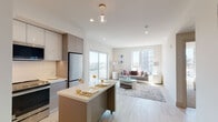 Located on Melrose Avenue in the heart of Los Angeles, this modern model unit showcases a thoughtfully designed open-concept floor plan that seamlessly connects the kitchen, dining, and living areas. Light wood-style flooring runs throughout, complementing the crisp white walls and neutral tones that define the space's contemporary aesthetic.

The kitchen is outfitted with sleek, two-tone cabinetry in white and warm gray, a full suite of stainless steel appliances including a French door refrigerator, microwave, and range, as well as a white quartz-topped island on casters — ideal for dining or entertaining. A classic white subway tile backsplash adds a clean, timeless touch.

The open living area is bathed in natural light from large floor-to-ceiling windows and a sliding glass door that frames views of the surrounding Los Angeles cityscape. Recessed lighting and a globe pendant fixture add warmth to the space.

The bedroom is generously proportioned, featuring a large picture window overlooking the neighborhood, light wood flooring, and ample closet space. The bathroom is finished with a floating gray vanity, an LED-backlit mirror, stone-look tile, and a combined soaking tub and glass-enclosed shower, creating a clean and spa-like atmosphere throughout.