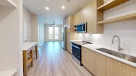 Located on Kerry Street in Savannah, Georgia, this thoughtfully designed one-bedroom, one-bathroom residence offers a clean, modern aesthetic throughout its efficiently arranged single-floor layout. Light wood-tone flooring runs through the main living areas, complementing the bright, neutral color palette that gives the space an open and airy feel.

The kitchen is a standout feature, outfitted with flat-front light wood cabinetry that extends to the ceiling for maximum storage, stainless steel appliances including a side-by-side refrigerator with ice maker, electric range, built-in microwave, and dishwasher. A herringbone-patterned tile backsplash and white quartz countertops add a refined, contemporary touch. Recessed lighting illuminates the space, which flows seamlessly toward glass French doors leading to an outdoor area.

The bedroom offers a comfortable, carpeted retreat with a ceiling fan, and a window with views of lush greenery that fills the room with natural light. The full bathroom features a walk-in glass-enclosed shower with marble-style tile, a wood-vanity with white countertop, and wood-look flooring. A dedicated laundry room includes a stacked washer and dryer unit alongside built-in wire shelving for additional storage. This residence combines practical functionality with modern design in the heart of Savannah.