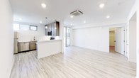 Located at 3008 Santa Monica Blvd in Santa Monica, California, this single-floor unit offers a clean, contemporary design throughout. Light-toned hardwood-style flooring runs continuously across the space, creating a cohesive and airy feel. The open-concept layout connects the kitchen and living area seamlessly, making the space feel expansive and functional. The kitchen is well-appointed with gray shaker-style cabinetry, sleek white quartz countertops, a classic white subway tile backsplash, and a full suite of stainless steel appliances including a gas range, over-the-range microwave, and additional appliances. Pendant lighting and recessed ceiling lights provide warm, layered illumination throughout. A ceiling-mounted cassette HVAC unit ensures efficient climate control. The living area is bright and open, with crisp white walls and access to a glass-panel door leading to an outdoor area. The bedroom is a quiet, well-proportioned space featuring a horizontal window with blinds that allows natural light while maintaining privacy. A generously sized walk-in closet with multi-tier shelving and hanging rods provides excellent storage. The unit's overall aesthetic is modern and move-in ready, with a neutral palette that offers a versatile canvas for any style.
