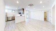 Located at 3008 Santa Monica Blvd in Santa Monica, California, this single-floor unit offers a clean, contemporary design throughout. Light-toned hardwood-style flooring runs continuously across the space, creating a cohesive and airy feel. The open-concept layout connects the kitchen and living area seamlessly, making the space feel expansive and functional. The kitchen is well-appointed with gray shaker-style cabinetry, sleek white quartz countertops, a classic white subway tile backsplash, and a full suite of stainless steel appliances including a gas range, over-the-range microwave, and additional appliances. Pendant lighting and recessed ceiling lights provide warm, layered illumination throughout. A ceiling-mounted cassette HVAC unit ensures efficient climate control. The living area is bright and open, with crisp white walls and access to a glass-panel door leading to an outdoor area. The bedroom is a quiet, well-proportioned space featuring a horizontal window with blinds that allows natural light while maintaining privacy. A generously sized walk-in closet with multi-tier shelving and hanging rods provides excellent storage. The unit's overall aesthetic is modern and move-in ready, with a neutral palette that offers a versatile canvas for any style.