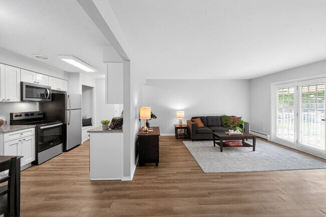 Cocina y sala de estar contemporáneas de planta abierta con electrodomésticos elegantes, suelos de madera noble y abundante luz natural. - University Oaks