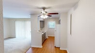 This 2-bedroom, 1-bathroom residence in Austin, TX presents a well-organized single-floor layout designed for comfortable everyday living. The living area features warm wood-look flooring and a ceiling fan with integrated lighting, creating a bright and airy atmosphere. Vertical blinds allow for adjustable natural light, while an open sightline connects the living space to the kitchen.

The galley-style kitchen is efficiently designed with gray cabinetry, light countertops, a stainless steel sink, recessed lighting, and a window that brings in natural light. White appliances, including a refrigerator and range, are neatly integrated along the corridor layout.

Both bedrooms are carpeted and feature ceiling fans with lighting fixtures, windows with blinds that frame views of surrounding greenery, and a calm, neutral color palette. The primary bedroom is generously sized and includes access to a dedicated walk-in closet outfitted with dual hanging rods on opposing walls, offering ample storage.

The bathroom is clean and functional, featuring a full tub-shower combination with white tile surround and brushed nickel fixtures. Hallways connect the spaces efficiently, contributing to a cohesive and practical floor plan throughout this Austin residence.