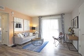 This single-floor residence at 6000 Montano Plaza Dr NW in Albuquerque, New Mexico, offers a well-designed layout with a contemporary aesthetic throughout. The living room is bright and welcoming, featuring wood-look flooring, a large sliding glass door with vertical blinds that allows generous natural light to fill the space, and access to the outdoors. A dedicated sitting nook adjacent to the living area adds functional versatility.

The galley-style kitchen is efficiently arranged with white cabinetry, granite-look countertops, a stainless steel sink, and black appliances including a refrigerator, range, and dishwasher. The adjoining dining area accommodates a round table and seating for four, anchored by a teal accent wall that adds a pop of color.

The primary bedroom is a restful retreat highlighted by a bold teal accent wall, plush carpeting, and a walk-in closet. A second bedroom offers carpeted flooring, a ceiling light fixture, and a window with drape treatments. Both bathrooms are thoughtfully finished — the full bath includes a vanity with a speckled countertop, wood-look flooring, and a tub/shower combination, while the half bath features stylish accent walls with decorative artwork. The overall ambiance is modern, cohesive, and move-in ready.