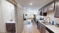 Located at 6313 Clinton Hwy in Knoxville, Tennessee, this single-floor studio unit offers a thoughtfully designed open-concept layout that efficiently combines living, dining, and sleeping areas into one cohesive space. Light hardwood-style flooring runs throughout, lending warmth and continuity from room to room.

The kitchen is a standout feature, outfitted with rich dark-toned cabinetry, white quartz-style countertops, and a classic subway tile backsplash. Stainless steel appliances — including an electric range, over-the-range microwave, dishwasher, and full-size refrigerator — provide a complete cooking setup. A single-basin sink with a modern gooseneck faucet anchors the counter space.

The open living and sleeping area is bright and airy, with a ceiling fan providing comfort and a window with blinds allowing natural light to filter in. A decorative room divider tastefully separates the sleeping area from the living space, which features room for a sectional sofa and a dining table with stools. A wall-mounted television and dresser complete the living area.

The bathroom is clean and functional, with dark cabinetry matching the kitchen, a white countertop vanity, a full tub-shower combination, and wood-look flooring. Recessed lighting throughout the unit adds a polished finishing touch to this compact yet complete space.