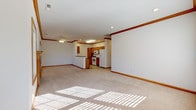 Located at 95 Hockanum Blvd in Vernon Rockville, Connecticut, this single-floor residence offers a well-designed layout with consistent warm wood trim and neutral tones throughout. The open-concept living and dining area is generously sized, featuring plush carpeting, crown molding, recessed lighting, and a ceiling fan. Natural light streams in through multiple windows, brightening the space considerably.

The kitchen is efficiently organized with warm oak cabinetry, dark granite-style countertops, a peninsula with a sink, and tile flooring. White appliances including a range, microwave, refrigerator, and dishwasher are included. A skylight adds additional brightness to the kitchen area.

A spacious living room features a wood-mantled fireplace flanked by windows, providing a comfortable focal point for the space. Carpeted bedrooms are well-proportioned, with ceiling fans, generous closet access via solid wood panel doors, and natural light from large windows offering neighborhood views.

Bathrooms are finished with tile flooring and oak vanities. The primary bathroom includes a dual-sink vanity with a large mirror, while a secondary bathroom offers a single vanity with an oval mirror and a bright window. Crown molding and coordinated wood trim unify the aesthetic throughout the entire residence.