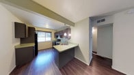 Located at 4805 Marquette NE in Albuquerque, New Mexico, this single-floor residence offers a thoughtfully designed layout with a seamless flow between living spaces. The kitchen serves as a central highlight, featuring dark espresso-toned cabinetry that contrasts beautifully with light countertops. A kitchen peninsula with an integrated sink provides additional prep space and casual seating potential, while pendant lighting overhead adds a warm, inviting ambiance. Black appliances, including a refrigerator and range, complement the contemporary color palette. Rich hardwood-style flooring extends throughout the space, lending warmth and continuity to each room. A window in the kitchen area allows natural light to filter in, brightening the space and offering a view of the surrounding greenery. Neutral walls in soft green and cream tones create a calm, versatile backdrop suitable for a variety of interior styles. A connecting hallway leads to additional areas of the home, hinting at a functional and well-organized floor plan. The textured ceiling adds a subtle architectural detail, while HVAC venting ensures year-round comfort. Overall, this residence offers a clean, modern aesthetic in a convenient Albuquerque location.