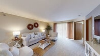Located at 1225 Deerfield Parkway in Buffalo Grove, IL, this single-floor, three-bedroom, one-bathroom home offers a well-organized layout with comfortable living spaces throughout. The living room is generously sized, featuring plush carpeting, a ceiling fan, and a large sliding glass door that fills the room with natural light while providing outdoor access. The open flow connects seamlessly to a dining area, making the space ideal for everyday living and entertaining. The kitchen is positioned centrally within the layout, offering convenient access to both the dining and living areas. The primary bedroom is notably spacious, complete with a walk-in closet and soft carpet flooring. A second bedroom offers a cozy retreat with a closet, natural window light, and a warm, intimate ambiance. The third bedroom, versatile in nature, can serve as a home office or guest room. The full bathroom is well-appointed with a single vanity, medicine cabinet storage, a mirror, and a tub-shower combination with tile surround and wood-tone accents. Neutral tones, warm lighting, and carpet flooring throughout contribute to a cohesive and inviting atmosphere across the entire home.