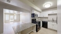 This well-appointed single-floor unit offers six bedrooms, four full bathrooms, and a practical layout designed for comfortable everyday living. The open-concept kitchen flows directly into the living area, creating a connected and social space. The kitchen is outfitted with crisp white shaker cabinets, granite countertops, a stainless steel sink, and black appliances including a range, over-the-range microwave, dishwasher, and refrigerator. A peninsula counter provides additional prep space and a natural divider between the kitchen and living room. The living area features light wood-style flooring, a ceiling fan, and double doors that invite natural light from outside. Bedrooms are carpeted and each include a ceiling fan and window with blinds, providing a comfortable and private retreat. Four full bathrooms are consistently finished with granite-topped vanities, white shaker cabinetry, and tiled shower-tub combinations. Four closets throughout the unit offer generous storage, including spacious walk-in options with wire shelving. A dedicated laundry room houses a washer, water heater, and electrical panel, adding further convenience. Neutral tones and consistent finishes throughout give the space a clean, cohesive aesthetic.