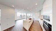 Located on a high floor at 2014 Fairview Ave in Seattle's South Lake Union neighborhood, this sophisticated residence offers a seamlessly designed open-concept layout bathed in natural light. Expansive floor-to-ceiling windows and curved glass panels wrap the living area, framing sweeping panoramic views of the Seattle skyline and surrounding cityscape.

The chef's kitchen is a standout centerpiece, featuring a generous waterfall-edge marble island with a deep dual-basin sink and gold-toned faucet, sleek flat-panel white cabinetry extending to the ceiling, a marble tile backsplash, gas cooktop, and built-in oven and microwave. Rich hardwood flooring flows throughout the entire residence, complementing the clean white walls and recessed lighting.

The living and dining areas are expansive and light-filled, anchored by the dramatic curved window wall with a structural column as an architectural focal point. The bedrooms are well-proportioned, each with hardwood floors, large windows offering city views, and access to well-appointed hallways with ample closet space.

The primary bathroom is a luxurious retreat finished in dramatic veined marble tile, featuring a freestanding soaking tub, glass-enclosed shower with gold fixtures, a dual-sink vanity with a dark stone countertop, and backlit mirrors — delivering a refined, spa-like experience.