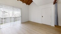 Located at 1560 S Highland Ave in Fullerton, CA, this one-bedroom, two-bathroom residence offers a thoughtfully designed single-floor layout. The living and dining areas are bright and airy, bathed in natural light through large windows dressed with sheer curtains, and finished with light-toned hardwood flooring throughout. A standout architectural feature is the vaulted ceiling with exposed wood beams in the living area, adding warmth and character to the open space. Sliding glass doors lead to a private balcony, providing an outdoor retreat with views of the surrounding area. The kitchen is equipped with stainless steel appliances, including a range, microwave, and dishwasher, complemented by sleek white cabinetry and a peninsula counter that opens to the dining space, making it ideal for both cooking and entertaining. Two closets offer ample storage throughout the unit. The bedroom is a quiet, well-proportioned space with clean white walls and matching hardwood floors. Both bathrooms are finished in a clean, neutral palette; one features a full soaking tub and shower combination with built-in shelving and brushed bronze fixtures, set above wood-look flooring. The overall ambiance is clean, modern, and move-in ready.