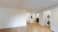 Located at 8106 SE Lake Rd in Portland, OR, this single-floor apartment offers a practical and well-organized layout across three bedrooms and two bathrooms. The combined kitchen and living room serves as the heart of the unit, with light wood-tone flooring, a baseboard heating system, and a sliding glass door that opens to a private balcony with outdoor views. The kitchen features white cabinetry, light countertops, a stainless steel sink, a dishwasher, and a full-size refrigerator, providing ample functionality for everyday use.

The three bedrooms are carpeted and share a consistent, clean aesthetic with white walls and textured ceilings. Each bedroom includes a window fitted with vertical blinds that let in natural light while offering a view of surrounding greenery. The primary bedroom is a comfortable size and includes built-in closet shelving for storage. Additional bedrooms also feature closet space and baseboard heating.

The two bathrooms are finished with light wood-tone flooring, white vanities, and light countertops. One bathroom includes a full tub-shower combination with a curved curtain rod, while the other offers a vanity with a sink and mirror. A dedicated laundry room adds everyday convenience to this thoughtfully arranged home.