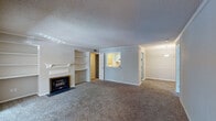Located at 321 Calibre Chase Dr in Raleigh, NC, this single-floor residence offers a well-organized layout designed for comfortable everyday living. The spacious living room serves as the heart of the home, anchored by a fireplace flanked by built-in shelving units — an ideal combination of warmth and display storage. Plush carpet runs throughout the living and bedroom areas, while wood-look flooring adds contrast in the kitchen and bathrooms. Crown molding and textured ceilings are consistent throughout, lending a classic finish to the interior.

The living area connects seamlessly to a dedicated dining space, illuminated by a pendant light fixture, and flows toward the kitchen via a pass-through window. The kitchen is equipped with stainless steel gas range and dishwasher, white shaker-style cabinetry, light stone-look countertops, and a single-basin sink.

Bedrooms are carpeted and well-lit, with one featuring a ceiling fan, multiple windows with outdoor views, and a sliding glass door that opens to an exterior space. Both bathrooms include white vanities with stone-look counters, wood-look flooring, and tub-shower combinations.