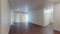This single-floor residence offers a practical and comfortable layout designed for everyday living. The open living area is a standout feature, showcasing rich, dark hardwood-style flooring that extends throughout the main living spaces, complemented by crisp white walls and vertical blinds that filter natural light from a large sliding glass door. The spacious feel of the living area is enhanced by clean sightlines leading down a hallway to the private quarters.

The kitchen is well-equipped with rich cherry-toned cabinetry, stainless steel appliances including a range, microwave, and refrigerator, along with a dishwasher and a tile backsplash that adds a decorative touch. Light countertops provide ample workspace, making the kitchen both functional and visually appealing.

The bedrooms are finished with soft, neutral carpeting and feature windows fitted with blinds that allow natural light to brighten each room. The primary bedroom includes direct access to a private bathroom, offering added convenience. The bathrooms are finished in a clean, all-white palette, with one featuring a tub-shower combination with built-in shelving, and another with a vanity, mirror cabinet, and chrome fixtures. The overall ambiance throughout the unit is clean, neutral, and move-in ready.