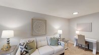 This renovated two-bedroom, one-bathroom single-floor residence offers a well-designed layout that maximizes comfort and functionality. The living room serves as a welcoming central space, featuring soft neutral walls, plush carpeting, and windows that invite natural light, creating a bright and airy atmosphere suited for both relaxing and entertaining.

The kitchen has been thoughtfully updated with white shaker-style cabinetry, light granite-look countertops, a deep double-basin stainless steel sink, and stainless steel appliances including a refrigerator and microwave. Wood-look flooring grounds the kitchen and extends into the adjacent dining area, which features a casual high-top table setup alongside a window and convenient entryway access.

Both bedrooms are carpeted and finished in soft gray tones, offering a calm, restful environment. Each room provides ample space for standard bedroom furnishings, with windows allowing natural light. The shared full bathroom is clean and functional, featuring a tub-shower combination, a vanity with a large mirror, and neutral finishes throughout.

Overall, the unit presents a cohesive, move-in-ready aesthetic defined by updated finishes, a neutral color palette, and a practical single-level floor plan.