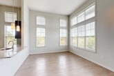 Located at 1000 Ellis Drive in Concordville, PA, this two-story residence offers a thoughtfully designed layout spread across two floors. The main level features an open-concept kitchen and living area, where the kitchen stands out with dark cabinetry, granite countertops, stainless steel appliances, and light hardwood flooring. The living room is bathed in natural light from large, floor-to-ceiling windows that frame lush, tree-lined views and contribute to the soaring ceiling height that defines the space. A hallway connects the main living areas, finished with clean flush lighting and hardwood-style flooring. The bathroom is well-appointed with large-format tile flooring, a dark vanity with granite countertop, and a walk-in glass-door shower. Both bedrooms feature soft carpeting and neutral walls, with the primary bedroom offering generous proportions. The upper floor hosts a loft that overlooks the main level, adding versatility to the floor plan. Additional features include multiple closets, a dedicated laundry area, and ample storage throughout. The light, neutral color palette and modern finishes create a clean, contemporary ambiance throughout the home.