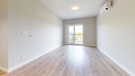 Located at 2840-2850 Carlow Rd in Victoria, BC, this well-appointed 2-bedroom, 2-bathroom unit offers a thoughtfully designed single-level layout. The open-concept kitchen and living area serves as the heart of the home, featuring a large island with a white quartz countertop, warm wood cabinetry, stainless steel appliances including a French door refrigerator and built-in microwave, and pendant lighting overhead. Light wood-style flooring runs throughout the main living areas, complementing the soft, neutral tones of the walls. The living room extends naturally toward a sliding glass door that opens to a balcony, filling the space with natural light and outdoor views. Both bedrooms are comfortably proportioned, each benefiting from large windows that bring in ample daylight and offer views of the surrounding greenery. The primary bedroom includes sliding door access to its own outdoor space and a dedicated mini-split unit for individual climate control. The two bathrooms are finished with warm wood vanities, bold-framed mirrors, and stone-look tile flooring, providing a clean, modern aesthetic. A hallway connects the rooms efficiently, and the overall design emphasizes a bright, contemporary feel throughout.