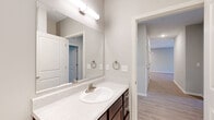This single-floor residence offers a thoughtfully designed open-concept layout that seamlessly connects the kitchen, dining, and living areas. The kitchen is a standout feature, equipped with rich dark-wood cabinetry, white quartz countertops, a generous central island, and a full suite of stainless steel appliances including a range, microwave, dishwasher, and refrigerator. Light wood-style flooring flows throughout the entire unit, creating a cohesive and contemporary aesthetic.

The living area is bright and airy, benefiting from abundant natural light streaming through French doors that open to a private balcony with outdoor views. A ceiling fan adds both style and comfort to the space. The bedrooms are well-proportioned, each featuring ceiling fans, large windows with views of surrounding greenery, and generous closet space — including a walk-in closet outfitted with wire shelving and hanging rods.

The bathrooms are finished with clean, neutral tones. The primary bath includes a large vanity with quartz countertops and dark wood cabinetry, a wide mirror with overhead lighting, and a glass-enclosed walk-in shower with brushed nickel fixtures. Neutral gray walls and white trim throughout the unit contribute to a fresh, modern ambiance.