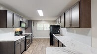 Located at 910 Shellbrook Ct in Raleigh, NC, this single-floor home offers a thoughtfully updated interior with a clean, neutral palette throughout. The renovated kitchen is a standout feature, showcasing dark and grey shaker-style cabinetry, striking marble-look countertops, a stainless steel double-basin sink, subway tile backsplash, and black stainless appliances including a range, refrigerator, microwave, and dishwasher. Wood-look plank flooring runs through the kitchen area, adding warmth and durability, while a skylight-style ceiling fixture provides ample overhead lighting. The bedrooms are carpeted and generously proportioned, each offering a comfortable, quiet retreat. Several rooms are equipped with ceiling fans and feature windows with blinds that bring in natural light and views of the surrounding greenery. The floor plan, as seen in the dollhouse view, reveals a well-organized layout with clearly defined living, kitchen, and bedroom zones connected by a central hallway. The bathroom includes a full tub-shower combination with white tile surround and chrome fixtures. Throughout the home, consistent neutral wall tones, white trim, and practical finishes create a cohesive and move-in-ready living environment.