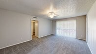 Located at 811 N Plymouth Rd in Dallas, TX, this single-floor unit offers three bedrooms and two bathrooms within a practical and well-organized layout. The living area is carpeted and bathed in natural light through sliding glass doors fitted with vertical blinds, and a ceiling fan adds comfort overhead. A textured ceiling is consistent throughout the home. The kitchen is a functional highlight, featuring a peninsula with white quartz-style countertops, dark cabinetry, wood-look plank flooring, a double-basin sink, and white appliances including a range, microwave, and refrigerator. A window above the sink brings in additional natural light. The spacious primary bedroom includes dual closets and a ceiling fan, providing ample storage and comfort. The additional bedrooms are carpeted and each feature ceiling fans with light fixtures and window coverings for natural light control. The bathrooms are finished with matching quartz-style countertops, dark vanity cabinets, large mirrors with overhead lighting, and a tub-shower combo with tiled surround. Wood-look flooring carries through the wet areas, tying the design together cohesively throughout this comfortable Dallas home.