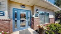 Located at 3603 Spring Villa Circle in Louisville, Kentucky, this single-story residential community property offers a thoughtfully designed and well-maintained exterior environment. The leasing office serves as the central hub of the community, identified by a prominent address marker and clearly labeled "Office" signage. Bold blue double doors with glass panels create an inviting and accessible entrance, complemented by brick accents, lap siding in neutral tones, and decorative wall-mounted lighting. Seasonal flower plantings add a welcoming touch to the entryway.

The grounds feature generously landscaped common areas with a variety of mature trees, ornamental grasses, and manicured shrubs set against fresh mulch beds and lush green lawns. A gently curving concrete walkway winds through the property, connecting key areas such as the communal mailbox station — housed in a dedicated brick-accented structure — to the parking areas and residential buildings. A circular drive entrance with a decorative island planting and an American flag display adds a distinctive and polished first impression.

Residential buildings display a consistent architectural style with beige lap siding, blue accent doors, iron-railed stairways, and covered entries. The open, park-like setting is further defined by a classic black split-rail fence that borders the property, creating a sense of defined space and pastoral charm under the open Kentucky sky.