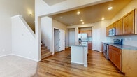 This three-story home is designed with a practical and open layout that flows naturally between its living spaces. The main level centers around a well-appointed kitchen that serves as the heart of the home. Warm-toned wood cabinetry pairs with granite countertops and a full suite of stainless steel appliances, including a French door refrigerator, range, and microwave. A central island with matching granite provides additional workspace and casual seating. Recessed lighting illuminates the kitchen, which opens to the surrounding living area. Rich hardwood flooring extends throughout the main level, adding warmth and continuity.

A carpeted staircase connects the floors, leading to the upper level where bedrooms feature plush carpet, neutral walls, and windows that bring in natural light. A full bathroom on this level includes a wood vanity with granite countertop, a tub-shower combination, and hardwood flooring.

The lower level presents an unfinished basement with concrete floors, exposed framing, and insulated walls, offering substantial potential for customization. A small window provides natural light to this versatile space, which is well-suited for future buildout.