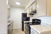 Located at 2601 E McKellips Rd in Mesa, AZ, this single-story apartment offers 720 square feet of thoughtfully arranged living space across 3 bedrooms, 2 bathrooms, and a kitchen. The living area features wood-look vinyl flooring, a ceiling fan with light fixture, and a sliding glass door that opens to a private balcony, filling the space with natural light and outdoor views. The kitchen is equipped with black appliances including a range, refrigerator, and dishwasher, complemented by light granite-style countertops and cream cabinetry with updated hardware. All three bedrooms are carpeted and feature ceiling fans; the primary bedroom spans 190 square feet and includes a window with natural light. The additional bedrooms are well-sized and share a clean, neutral aesthetic. Both bathrooms include a tub/shower combination with chrome fixtures and safety grab bars, with one bathroom featuring wood-look tile flooring and a vanity with cabinet storage. A dedicated closet provides additional storage. The unit's clean white walls and consistent finishes throughout create a bright, cohesive ambiance suited for comfortable everyday living.