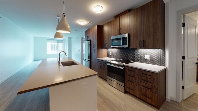 Our alternative option features cozy, chestnut-colored cabinets, paired with a chic, grey designer backsplash and quartz countertops. - Modera West Wash Park