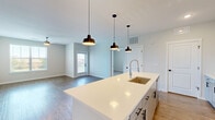 Located at 9292 Grand Cordera Pkwy in Colorado Springs, CO, this well-designed 2-bedroom, 2-bathroom single-floor residence offers a clean, modern aesthetic throughout. The open-concept kitchen is a standout feature, anchored by a large center island with a white quartz countertop, an undermount sink, and a sleek gooseneck faucet. Three matte black pendant lights hang above the island, adding a contemporary touch. White cabinetry with black hardware, a herringbone tile backsplash, and a full suite of stainless steel appliances — including a refrigerator, range, and over-range microwave — complete the kitchen. The adjacent living room features durable wood-look flooring, a ceiling fan, and large windows that invite abundant natural light and outdoor views. Both bedrooms are carpeted and equipped with ceiling fans, offering a comfortable and quiet retreat. The spacious primary bedroom connects to a well-appointed en-suite bathroom featuring a dual-sink vanity, wood-look flooring, and a glass-enclosed walk-in shower with marble-style tile surround. The second bathroom includes a soaking tub with a matching marble-style tiled surround. Each bedroom benefits from a dedicated closet, and two hallways connect the spaces efficiently throughout the home.