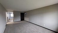 Located at 5150 16th Ave SW in Cedar Rapids, Iowa, this single-floor unit offers a practical and well-organized layout with consistent neutral tones and dark trim accents throughout. The living area is generously sized, featuring plush carpet flooring, smooth gray walls, and a textured ceiling, creating a clean and open atmosphere. A wall-mounted unit provides supplemental climate control in this space.

The kitchen is efficiently designed with rich dark espresso cabinetry offering ample storage, dark granite-style countertops, and a full suite of black appliances including a range, built-in microwave, dishwasher, and refrigerator. Light wood-look vinyl plank flooring runs through the kitchen and connecting hallway, providing a durable and attractive transition between spaces.

The bedrooms are carpeted and feature ceiling fans with light fixtures, baseboard heating units, and sliding windows that bring in natural light and views of the surrounding neighborhood. Dark-framed windows and doors provide a cohesive contrast against the neutral wall tones.

The bathroom includes a full tub and shower combination enclosed by sliding frosted glass doors, complemented by light wood-look flooring and cool blue-gray walls. A hallway with ample door access connects the main living areas, completing this straightforward and functional single-level layout.